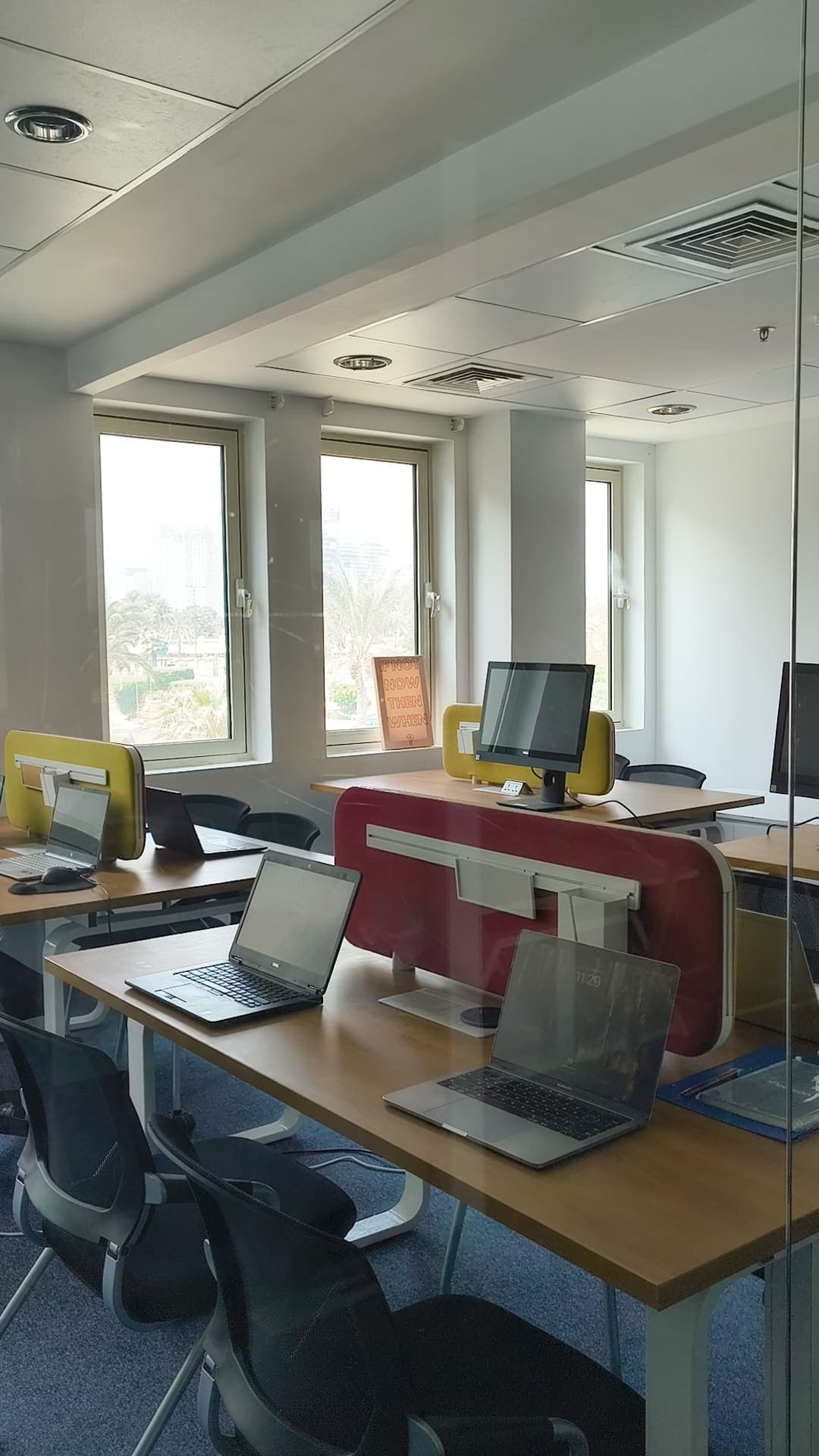 Shared desks and laptops in a TIIB study room, windows looking onto Dubai Knowledge Park